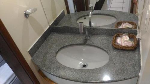 a bathroom with a sink with two baskets on it at Apart Hotel Quartier Latin in Vitória