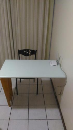 a white table and a chair in a room at Apart Hotel Quartier Latin in Vitória