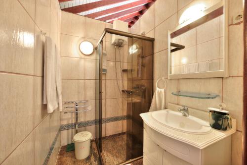 uma casa de banho com um lavatório e uma cabina de duche em vidro. em Residencial Cabo Verde Palace em Santa Maria