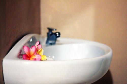 a bathroom sink with a flower on the top of it at Ulu Bali Homestay in Jimbaran