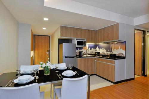 a kitchen with a table and white chairs in a room at Citadines Sukhumvit 11 Bangkok in Bangkok