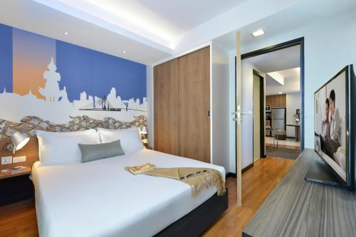 Citadines Sukhumvit 11 Bangkok في بانكوك: غرفة نوم بسرير ابيض كبير وغرفة معيشة