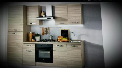 kuchnia z drewnianymi szafkami i piekarnikiem w obiekcie Alessi Suites & Studio w mieście Mazzarino