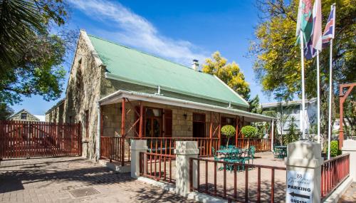 an old building with a green roof and a fence at 88 Baron van Reede Guesthouse in Oudtshoorn