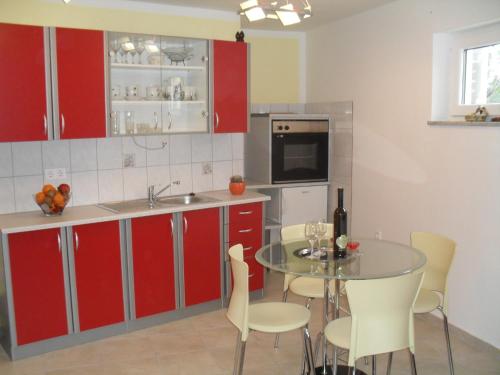 a kitchen with red cabinets and a table with chairs at Apartman Jurja in Ledenice