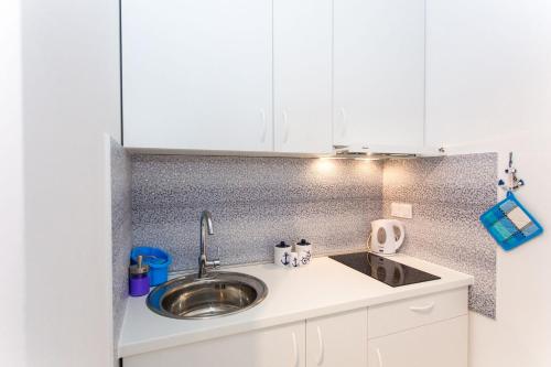 a kitchen counter with a sink and white cabinets at Korcula apartmanu Mili in Korčula