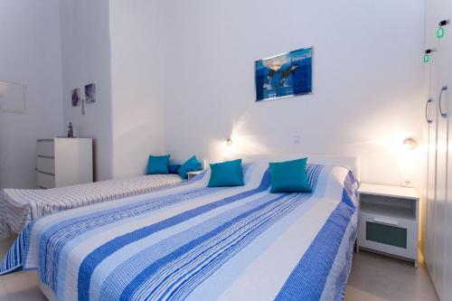 two beds in a white room with blue pillows at Korcula apartmanu Mili in Korčula