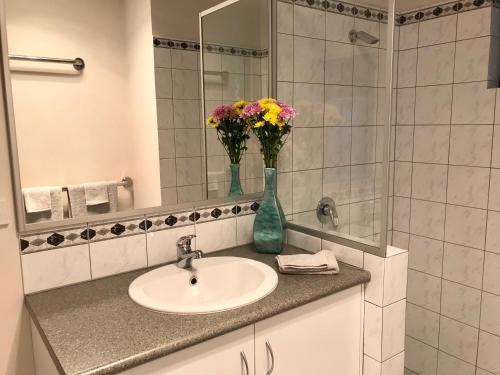 a bathroom with a sink and a mirror and flowers at Little Shangri-La in Busselton