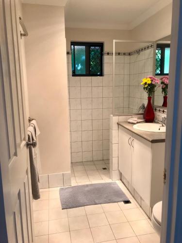 Baño blanco con lavabo y espejo en Little Shangri-La, en Busselton