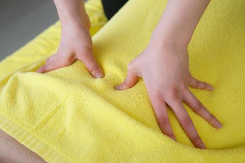 a person with their hands on a yellow pillow at Sauna & Capsule Hotel Rumor Plaza in Kyoto