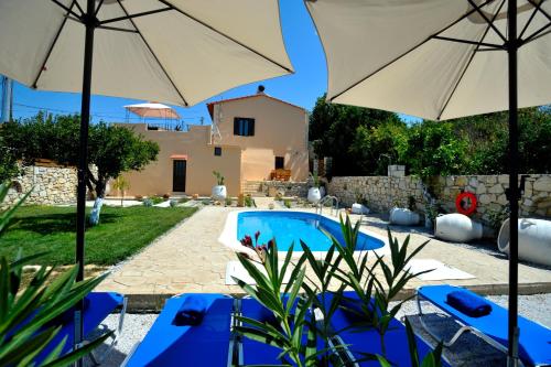a pool with blue chairs and umbrellas next to a house at Pithari Villa in Agios Dimitrios