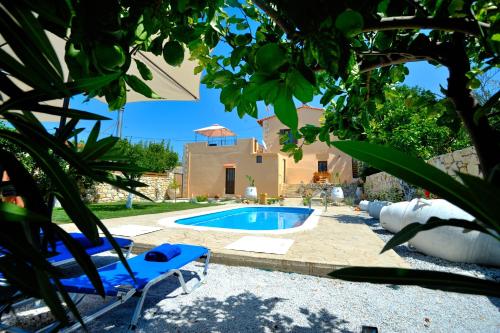 a pool in a yard with two lounge chairs and a house at Pithari Villa in Agios Dimitrios