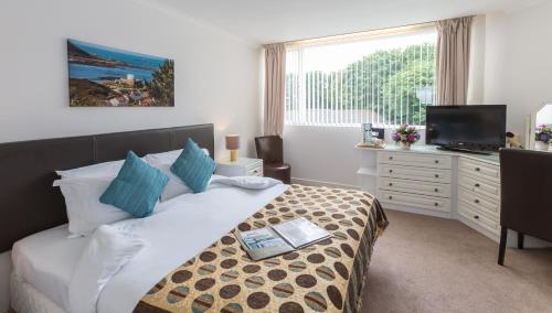 Schlafzimmer mit einem Bett, einem TV und einer Kommode in der Unterkunft La Collinette Hotel, Cottages & Apartments in St Peter Port