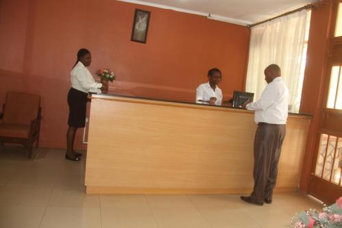 a couple of people standing at a reception counter at Bomen Hotel in Isiolo