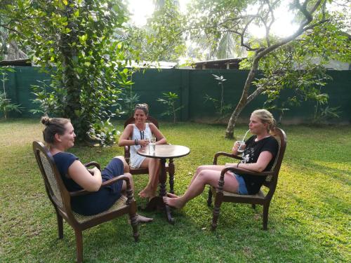 three women sitting at a table in a yard at Old Parkland Hostel in Galle