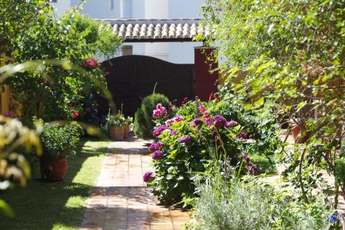 a garden with flowers and a brick walkway at Hotel Doñana Blues in Matalascañas