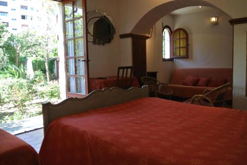 a bedroom with a red bed and a couch and window at Hôtel Castel Mistral in Juan-les-Pins