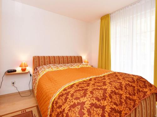 a bedroom with a bed with an orange bedspread and a window at Ferienwohnung-1a-7 in Baabe