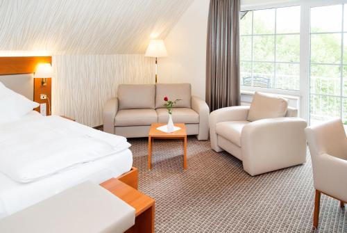 a hotel room with a bed and a couch and a chair at Ringhotel Teutoburger Wald in Tecklenburg