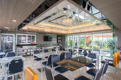 a dining room with tables and chairs and windows at B-your home Hotel Don Mueang Airport Bangkok 如你家酒店 in Bangkok