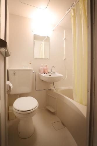 a white bathroom with a toilet and a sink at Hotel Yumeya in Fukuoka