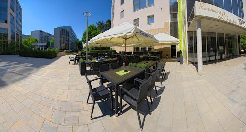 a group of tables and chairs with umbrellas outside a building at NOVINA HOTEL Südwestpark in Nürnberg