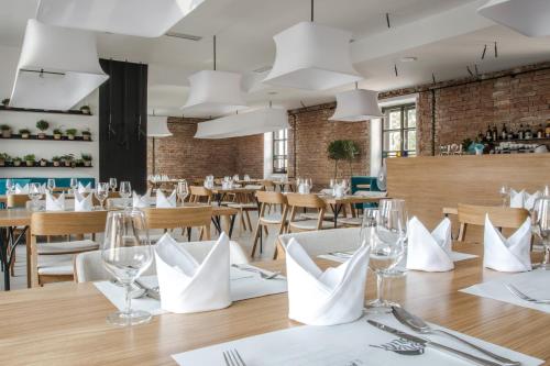 een restaurant met houten tafels en stoelen en witte servers bij Hotel Restaurant Na Návsi in Říčany u Brna