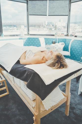 a woman laying on a bed in a room at Kyriad Prestige Hotel Clermont-Ferrand in Clermont-Ferrand