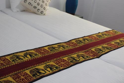 a bed with a yellow and red blanket on it at Selyna Sky Terrace in Kandy
