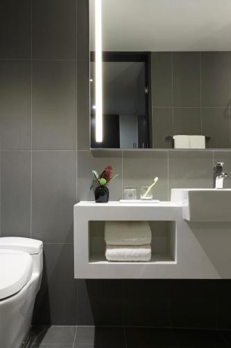 a bathroom with a sink and a toilet and a mirror at L7 GANGNAM by LOTTE in Seoul
