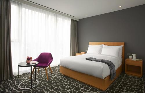 a hotel room with a bed and a purple chair at L7 GANGNAM by LOTTE in Seoul