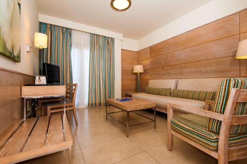 una camera d'albergo con un divano, un tavolo e una televisione di Kn Hotel Arenas del Mar Adults Only a El Médano