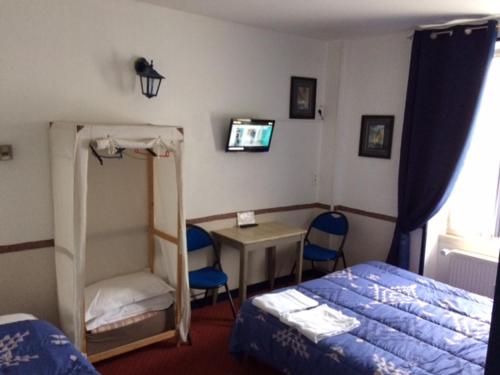 a bedroom with a bed and a desk and a bed and a table at Hôtel de la Gare in Saint Malo