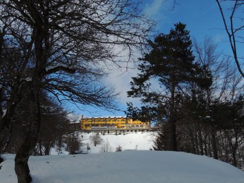 a yellow building on top of a snow covered hill at Grand Hotel Astoria in Lavarone