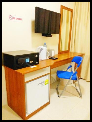a desk with a microwave and a television and a chair at Hulhan'gu Lodge in Himmafushi