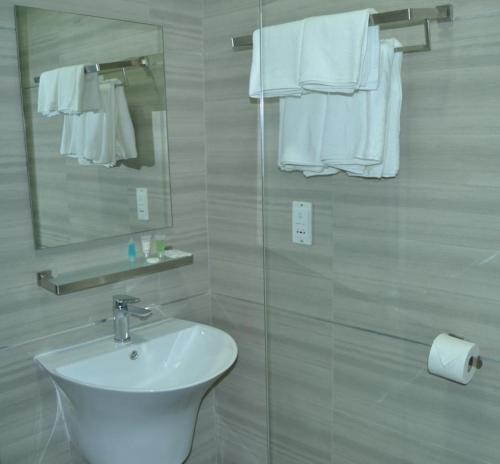 a bathroom with a sink and a mirror and towels at Phudzi Hotel in Letlhakawe
