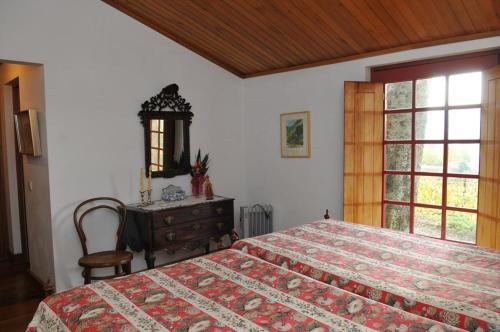 a bedroom with a bed and a dresser and a window at Casa do Silvério in Santa Cruz do Douro
