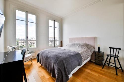 a bedroom with a bed and a desk and windows at Hôtel de ville in Levallois-Perret