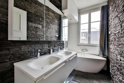 a bathroom with a white sink and a bath tub at Hôtel de ville in Levallois-Perret