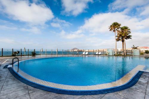 エル・メダノにあるKn Hotel Arenas del Mar Adults Onlyのヤシの木と海を望む大型スイミングプール
