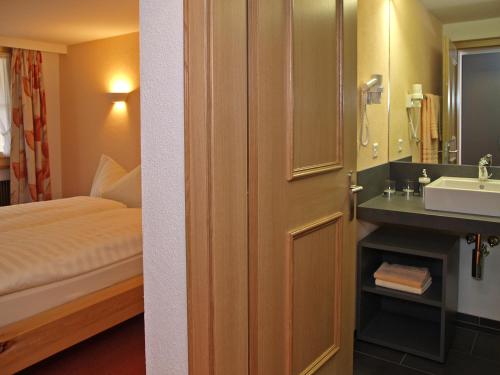 a bathroom with a bed and a sink next to a door at Hotel Steinbock in Brienz