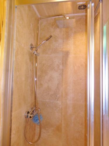 a shower with a shower head in a bathroom at Hour Glass Hotel in London
