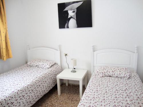 a bedroom with two beds and a table with a picture at Apartamentos Arinsal 3000 in Arinsal