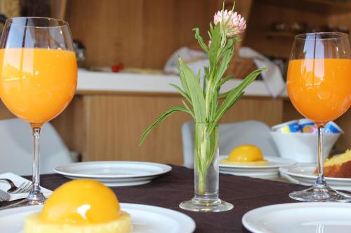 a table with two glasses of orange juice and a flower in a vase at Beleza Serra Guide Hotel in Geres