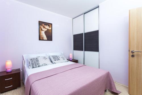 a bedroom with a bed with a pink blanket at Gold & Silver Apartments in Brna