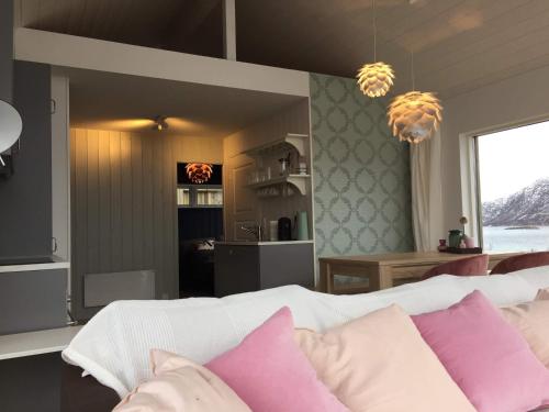 a bedroom with a white bed with pink pillows at Steigen Lodge Sjøhytter in Engeløya