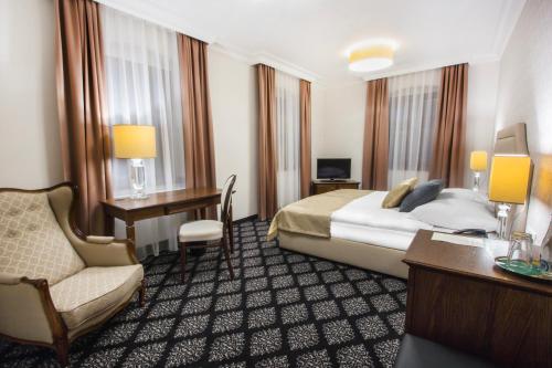 a hotel room with a bed and a desk and a chair at HG Hotel in Toszek