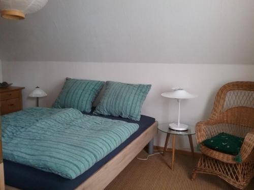 a bed with a blue comforter and a chair in a room at Altstadt-Apartment Petershagen in Petershagen