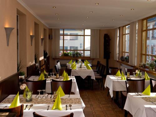 a restaurant with tables and chairs with yellow napkins on them at Gasthaus Metzgerei Pension Maßem in Schillingen