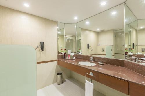 a bathroom with a sink and a large mirror at Hotel Naveen Lakeside in Hubli